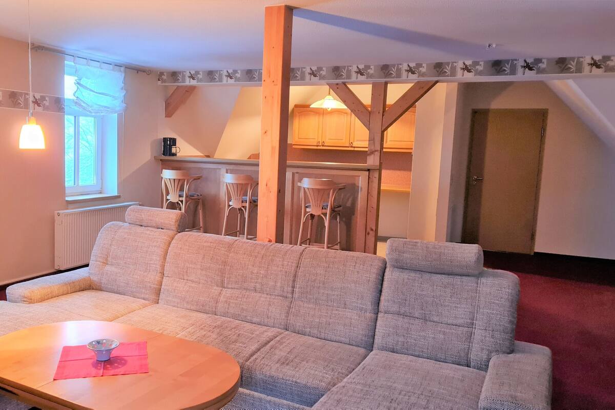 A cozy living room with a sofa, a wooden coffee table, and a window with curtains.