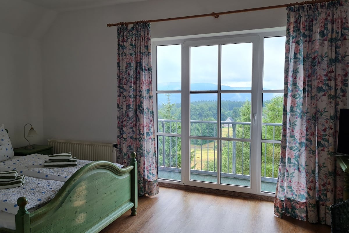 A bedroom with a bed, a nightstand, a lamp, and a window with curtains.