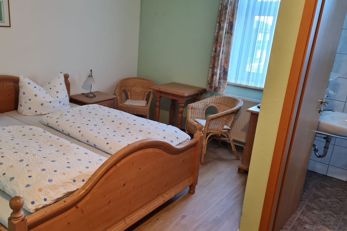 A bedroom with a wooden bed, two bedside tables, a chair, and a small table.