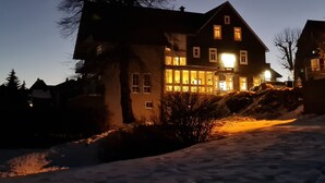 Una grande casa a più piani con un balcone sporgente, circondata dalla neve.