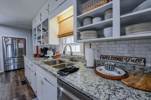 A modern kitchen with white cabinetry, granite countertops, and a 'WELCOME Y'all' sign. - Wright Spot - Book now for football season! Close to Campus! (Tuscaloosa)