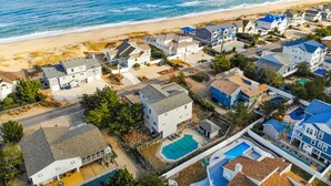 Vista aèria d'una zona residencial costanera amb cases, una platja i un cel serè.