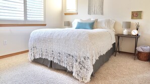 Una camera da letto con un letto grande, un comodino con una lampada, un elemento decorativo a parete e un piccolo quadro.