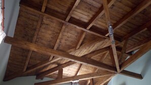 Ein Zimmer mit hoher Holzbalkendecke und einer an der Wand befestigten Klimaanlage.