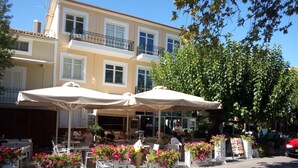 Ein Straßencafé mit Tischen und Stühlen, umgeben von Blumenkästen.