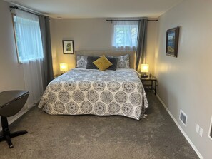 Ein Schlafzimmer mit einem großen Bett, zwei Nachttischlampen, einem Schreibtisch und einem Sessel.