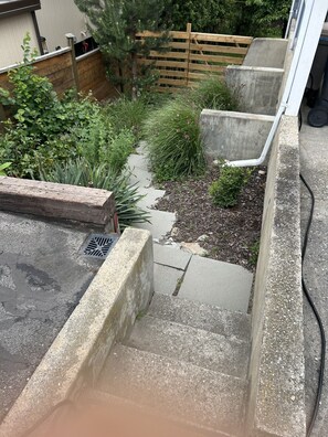 Eine Betontreppe führt zu einem Dachgarten mit Holzzaun und verschiedenen Pflanzen.