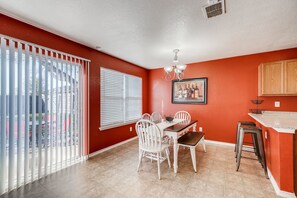 A dining area with a table and chairs, a window with blinds, and a kitchen area with a counter and stools. - BMT Grads Stay! Minutes to Lackland + Community POOL, SeaWorld, Shopping! (San Antonio)