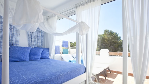 A bedroom with a bed, a window with curtains, and a view of the outside. - Bungalow Playa D'or, Delante de la Playa con Wifi, A/A y Piscina Comunitaria (Cala D'or)