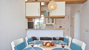 A dining area with a white table, blue chairs, and a fruit centerpiece. - Bungalow Playa D'or, Delante de la Playa con Wifi, A/A y Piscina Comunitaria (Cala D'or)