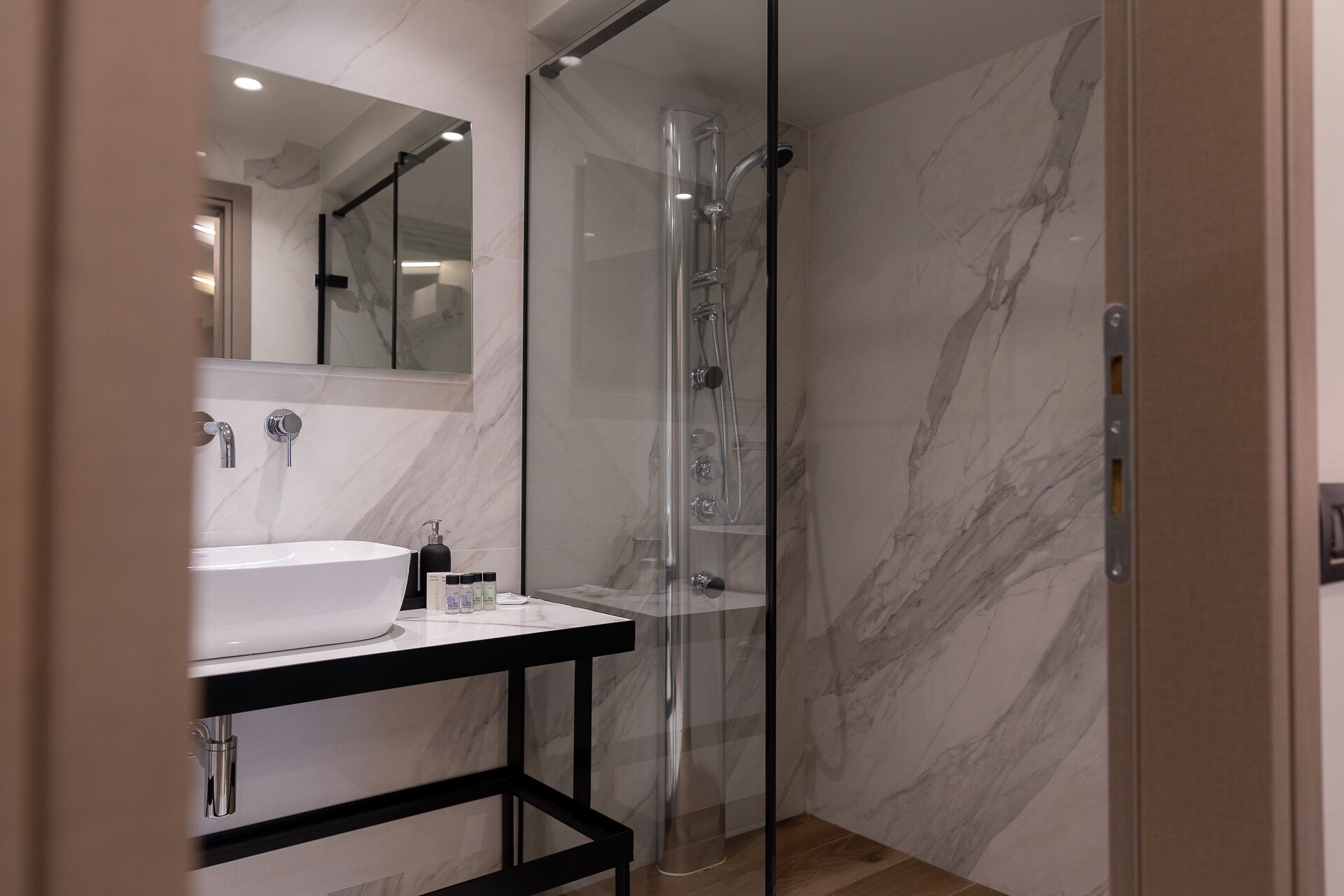 A modern bathroom with a glass-enclosed shower, a white sink, and a marble-tiled shower area.