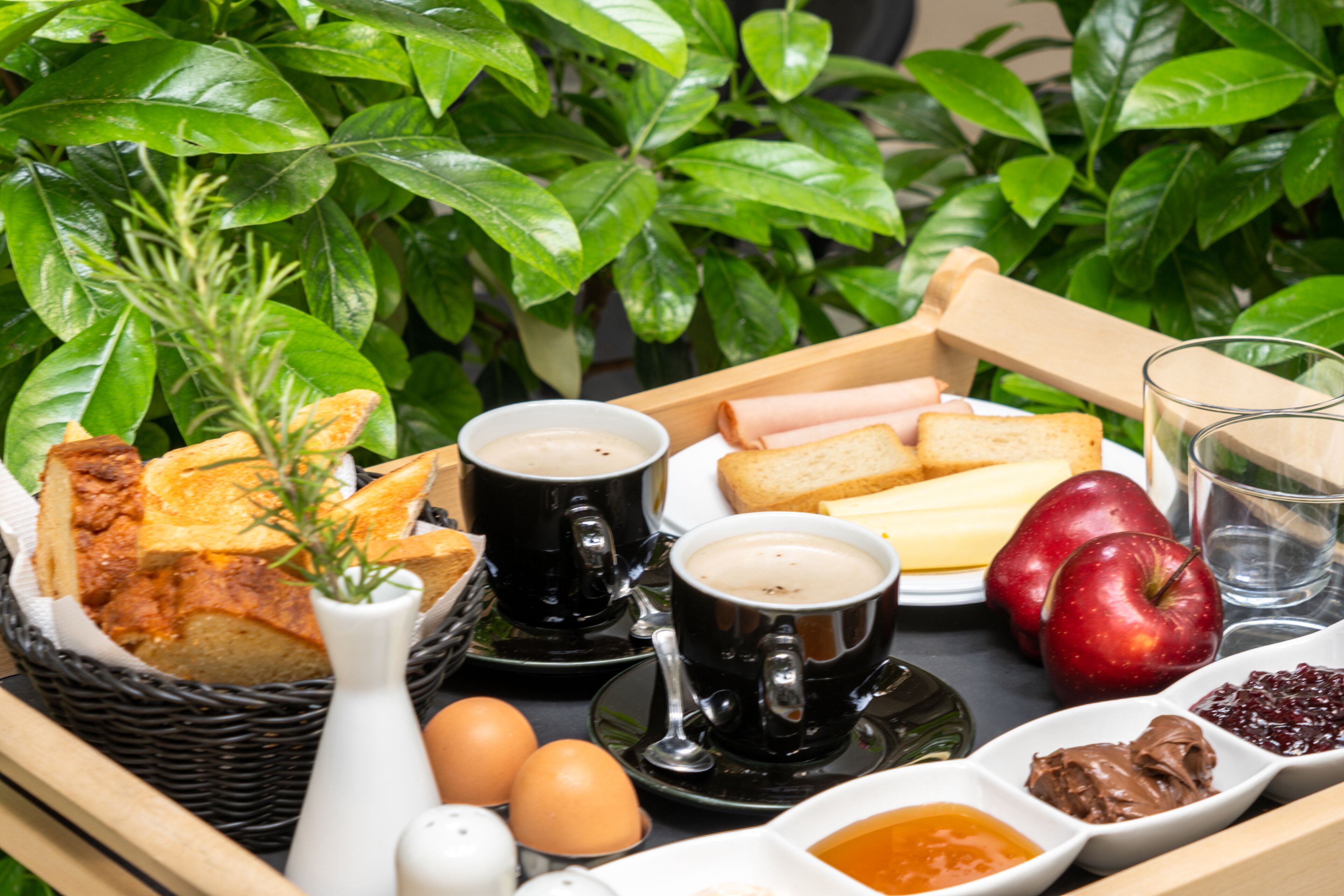 A tray with bread, eggs, coffee, and apples.