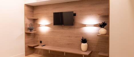 A modern living room with a built-in TV, wooden shelving, and a bench.