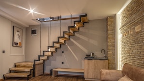 Un interior moderno con una escalera de madera, una zona de cocina y una pared de ladrillo.