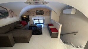 A living room with a sofa, a coffee table, and a TV. There is a staircase leading to another level. - Two steps from the sea and four from the historic center "Donizetti House" (Catania)