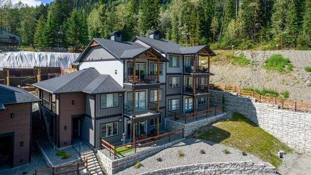 A multi-story building with a stone foundation, large windows, and balconies. - The Crowe's Nest @ Peaks West (Sun Peaks)