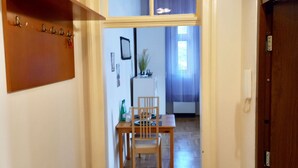 A hallway with a wooden floor, a dining area with a table and chairs, and a window with a view into another room. - Apartament Rachel Stare Miasto Basztowa 23 (Kraków)
