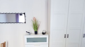 A room with a white wardrobe, a wooden chair, a sofa, a mirror, and a potted plant. - Apartament Rachel Stare Miasto Basztowa 23 (Kraków)