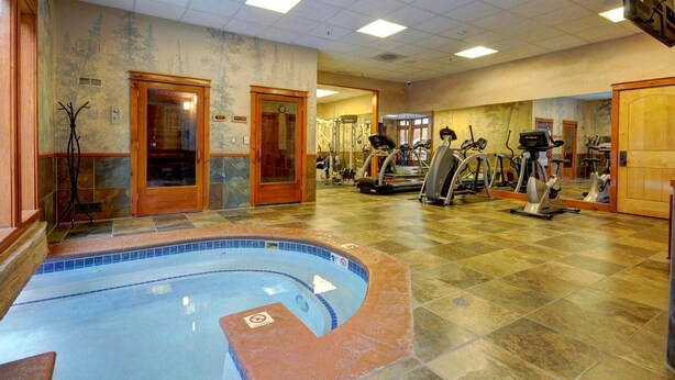Een fitnessruimte met een zwembad, trainingsapparatuur en een spiegelwand.