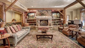 A spacious living room with a stone fireplace, leather sofas, and a large rug. - Luxury Ski in Ski out Condo/Pool and Hot Tub Access/Private Patio (Keystone)