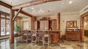 A rustic interior with a stone-tiled floor, wooden furniture, and a large wooden beam structure. - Luxury Ski in Ski out Condo/Pool and Hot Tub Access/Private Patio (Keystone)