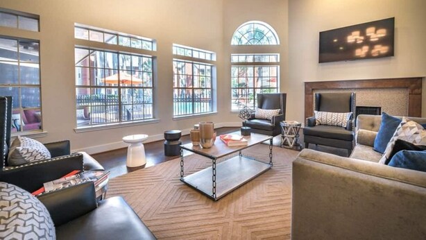 Un salón amplio con ventanas grandes, chimenea y una lámpara moderna.