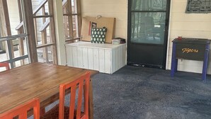 Une pièce avec une table en bois et des chaises rouges, un ventilateur de plafond et une porte avec une fenêtre.