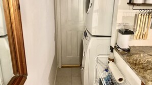 Un espace buanderie équipé d’un lave-linge, d’un sèche-linge et d’un plan de travail avec des ustensiles de cuisine.