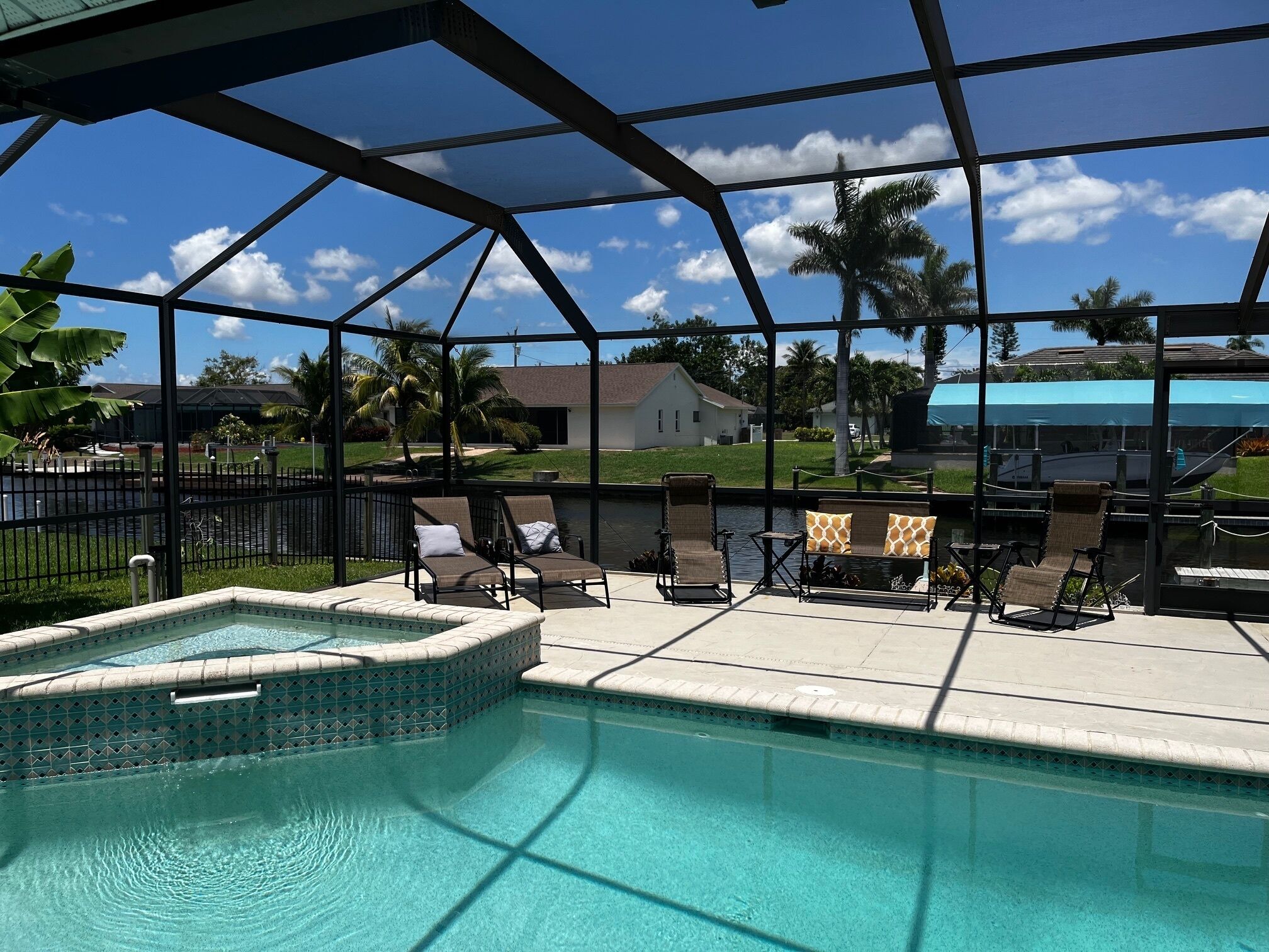 Un área de piscina con hidromasaje, sillones de descanso y vistas a un barrio residencial.