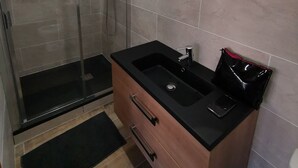 A bathroom with a glass shower enclosure, a black sink with a wooden vanity, and a gold-framed mirror. - Wellness in Sologne La Frenaudiere spa (2 Villa la fronodiere. Gy-en-Sologne)