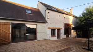 A rustic house with a wooden deck, a sliding glass door leading to a bathroom, and a brick wall. - Wellness in Sologne La Frenaudiere spa (2 Villa la fronodiere. Gy-en-Sologne)