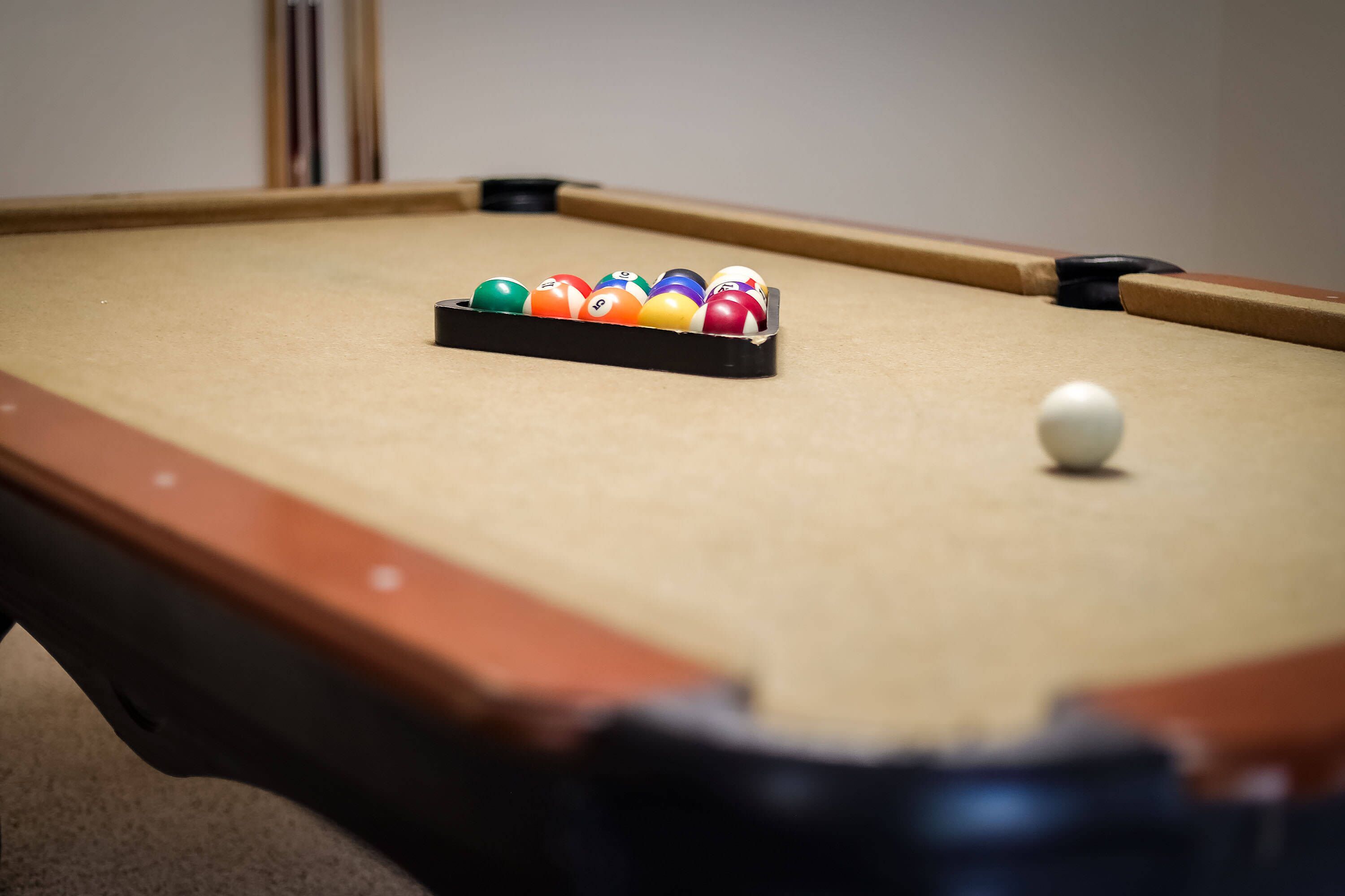 A pool table with a set of billiard balls in the center and a single white ball on the table.