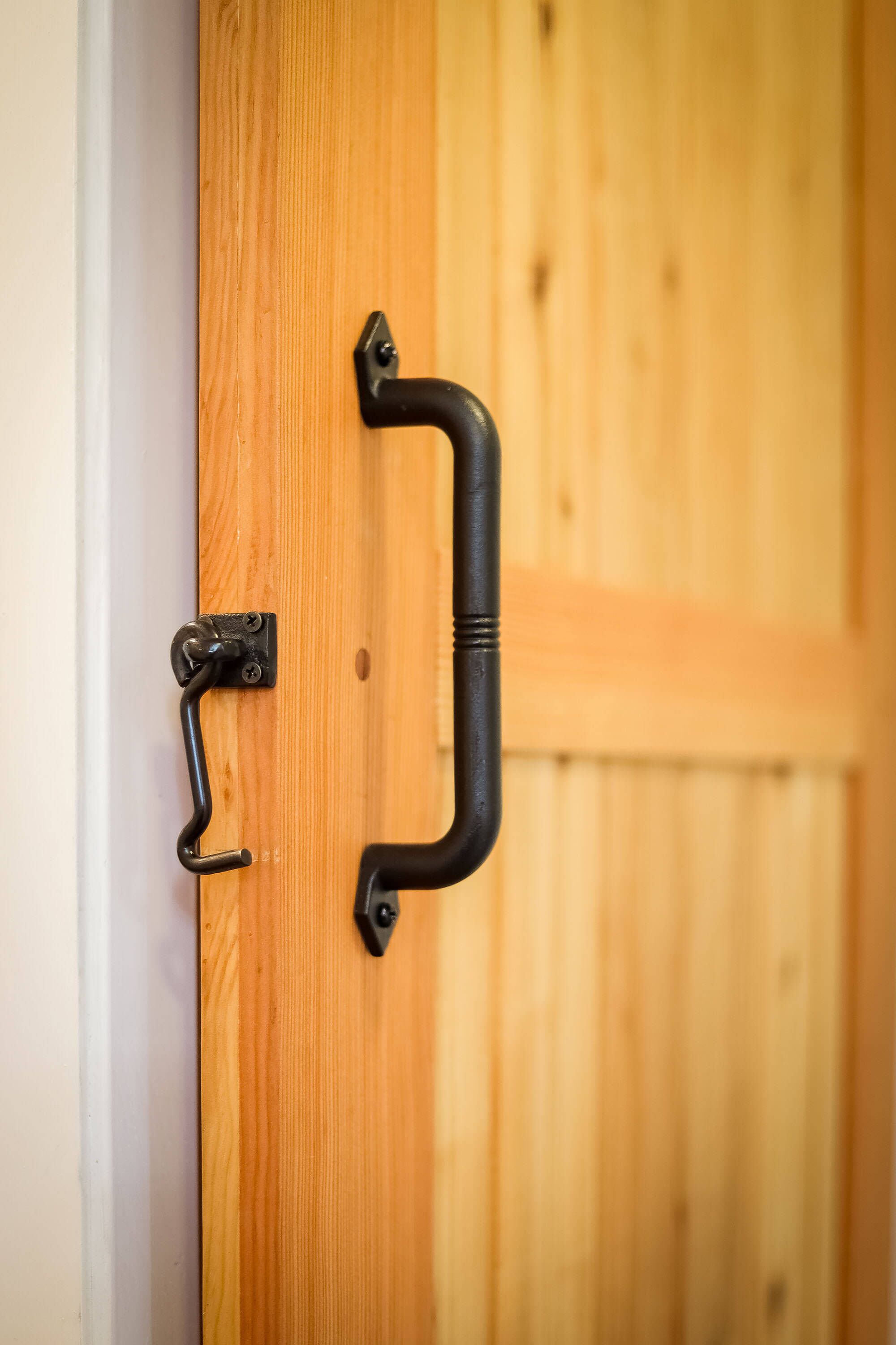 Una puerta de madera con manija y pestillo de metal negro.