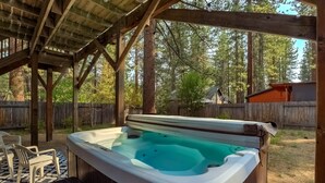 A hot tub under a wooden pergola with a wooden fence and trees in the background. - Paloma Place  Hot Tub | Game Room | Pool Table (South Lake Tahoe)