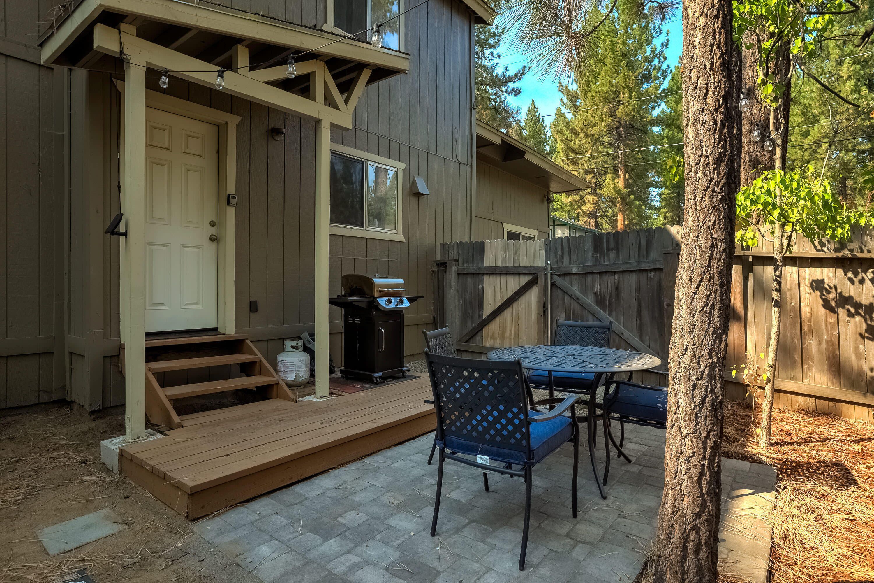 A patio with a wooden deck, a grill, and outdoor furniture.
