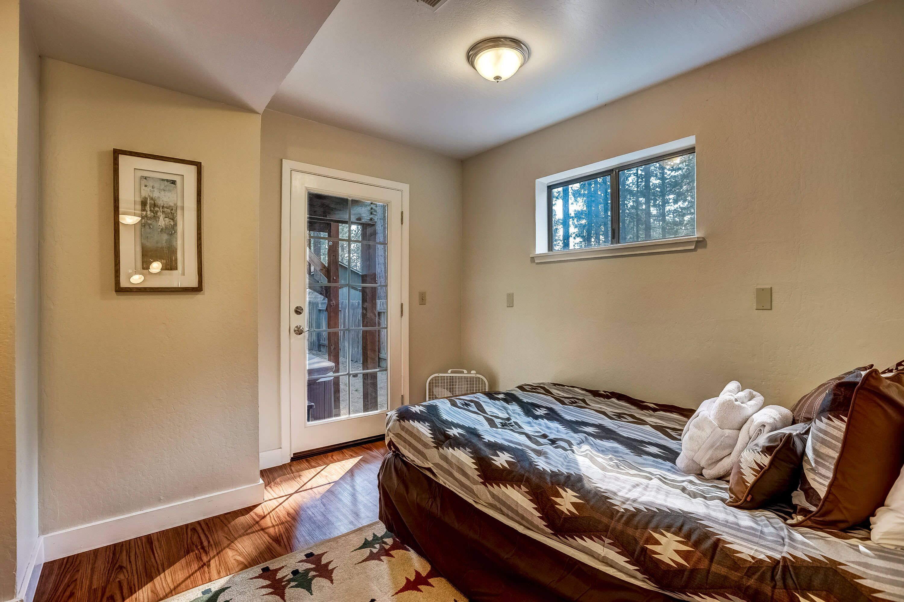 Un dormitorio con cama, ventana, puerta y una lámpara en el techo.