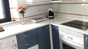 Una cocina compacta con lavadora, cafetera y horno empotrado.