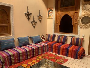 A traditional Moroccan room with a sofa set, patterned cushions, and a decorative mirror. - RIADJENANADAM Marrakesh (Marrakech)