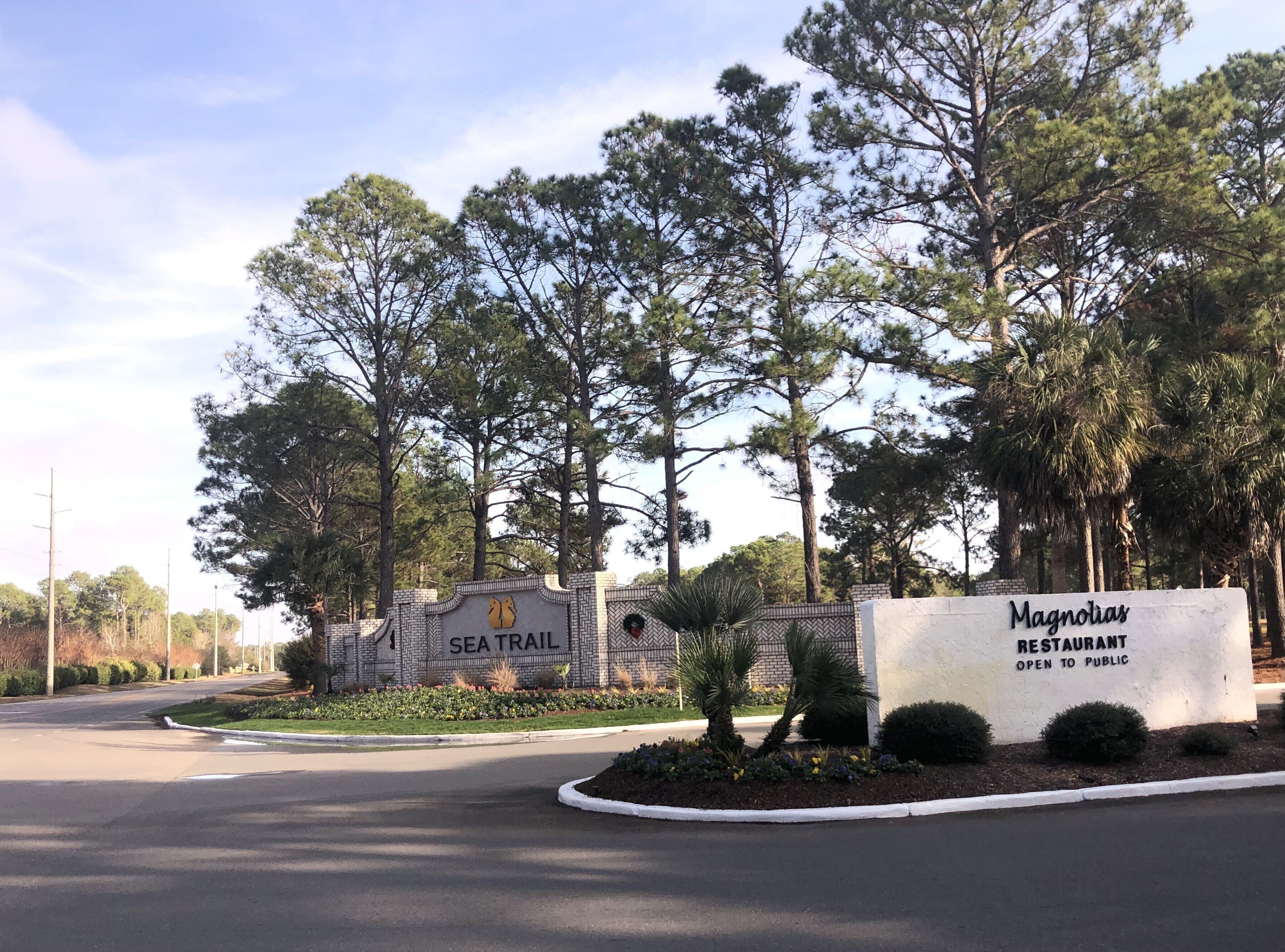 A sign for 'Magnolias Restaurant' and 'Sea Trail' with a landscaped area in front.
