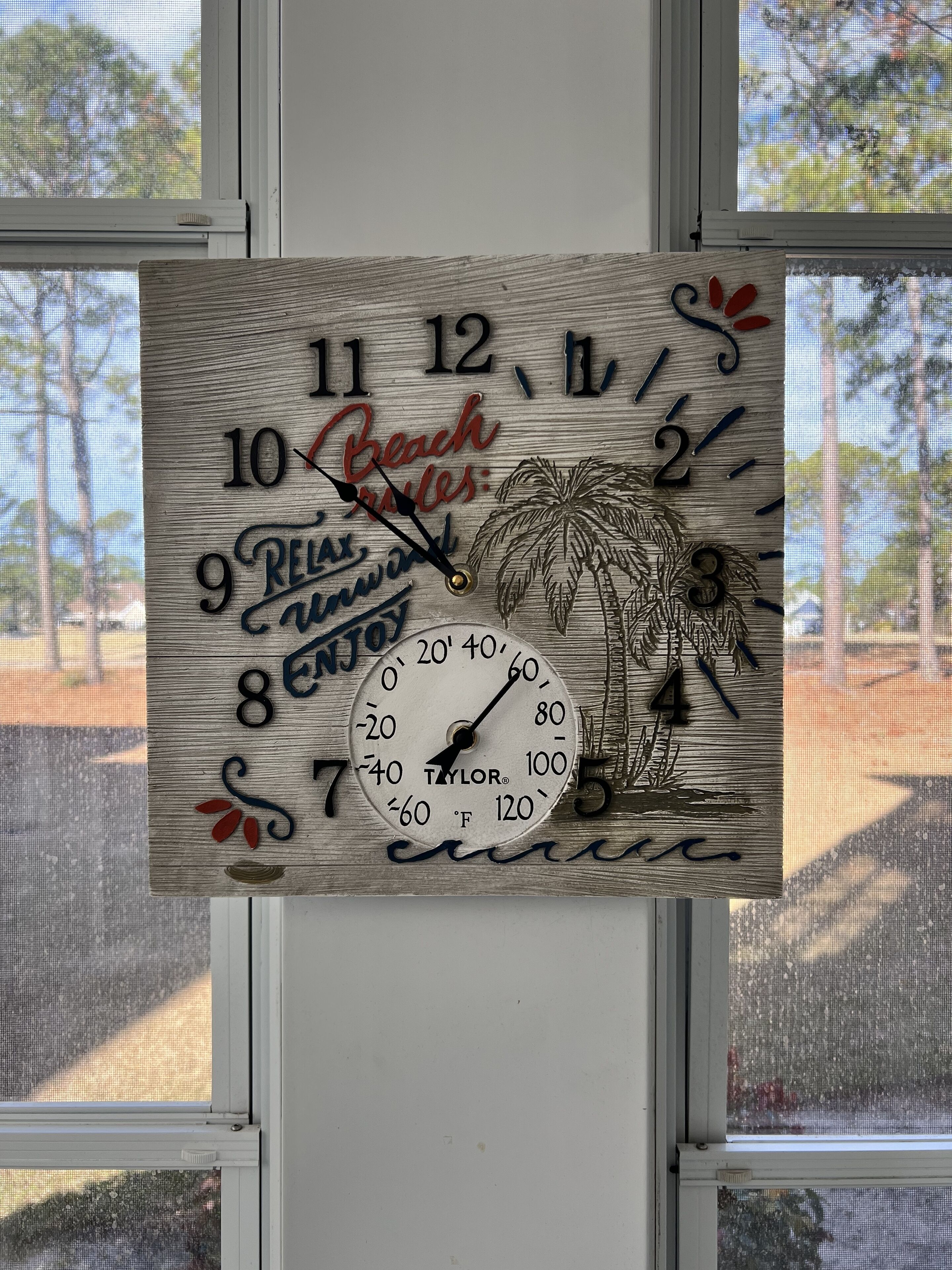 A wooden wall clock with a beach theme, including palm trees and the words "Relax Enjoy."