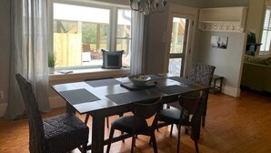 A dining area with a table and chairs, a chandelier, and a view of the outdoors.