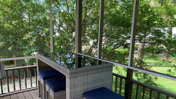 A covered outdoor area with wicker furniture and a railing.