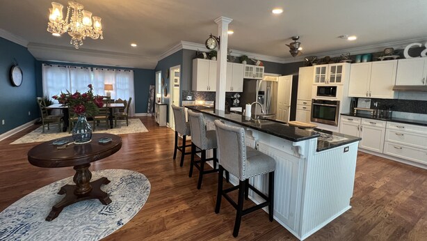 A modern kitchen with a central island, bar stools, and a chandelier.