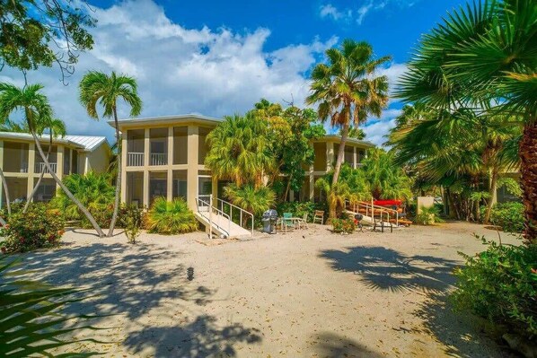 A resort with multiple buildings, palm trees, and a sandy beach area.