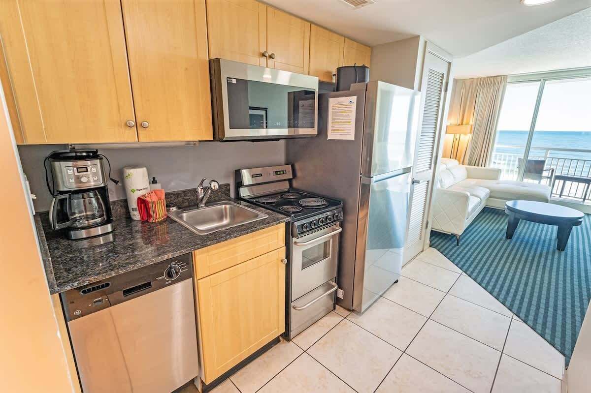 A modern kitchen with stainless steel appliances, wooden cabinets, and a view of the ocean.