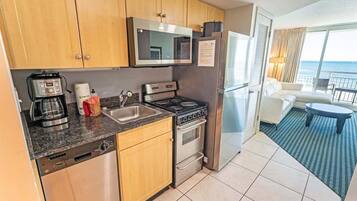 A modern kitchen with stainless steel appliances, wooden cabinets, and a view of the ocean.