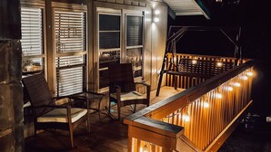 An outdoor deck with wooden railings and chairs, a wooden floor, and windows with blinds. - Spacious 3BR/3BA Cabin Only 0.5 Miles From Slopes! (Beech Mountain)