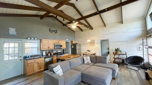 A spacious living area with a gray sectional sofa, wooden cabinets, a kitchen area, and a dining table. - Spacious 3BR/3BA Cabin Only 0.5 Miles From Slopes! (Beech Mountain)
