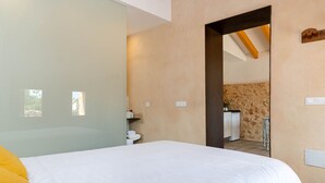 Un dormitorio con una cama, un baño pequeño y vistas a una zona de cocina.