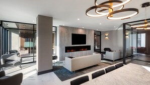 Een moderne woonkamer met een open haard, een grote flatscreen televisie en een moderne kroonluchter.
